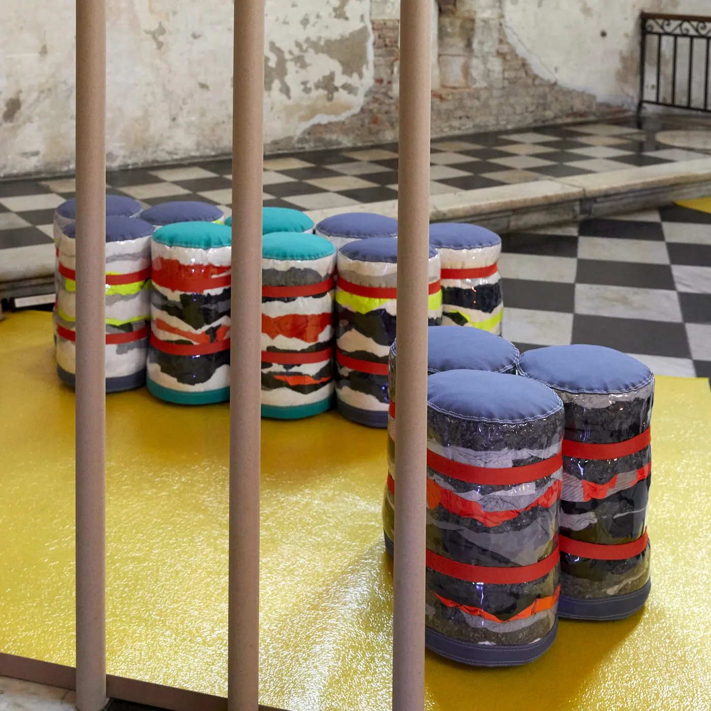 Assises cylindriques en matières textiles revalorisées, disposées sur un tapis jaune.
